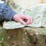 A person in high vis touching some camouflage fabric