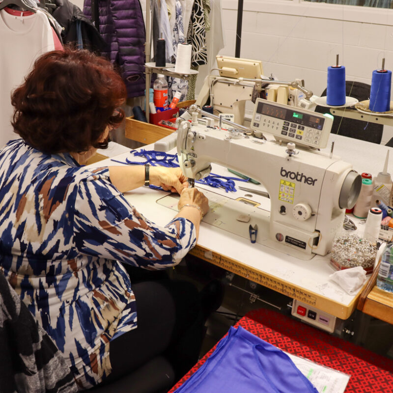 An image of a worker in a factory sewing some fabric